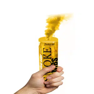 Fumigène à main jaune en activation, libérant une fumée dense et vibrante dans un espace extérieur.