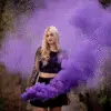Fumigène torche à main violet en pleine activation, libérant une fumée dense et colorée dans un environnement extérieur.