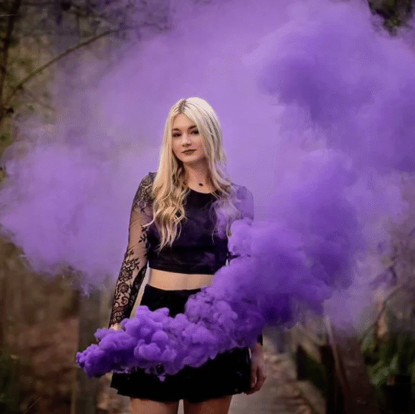 Fumigène torche à main violet en pleine activation, libérant une fumée dense et colorée dans un environnement extérieur.