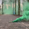 Fumigène vert avec goupille allumée, dégageant une fumée dense et colorée, idéal pour les événements festifs et les activités en extérieur.